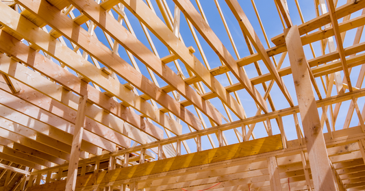Wooden roof trusses against a blue sky