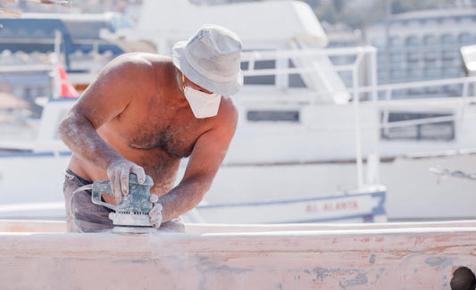 Shirtless man sanding the structure of a boat