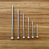 stainless steel eagle claw screws that come in the free sample pack on a wooden surface