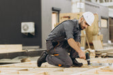 Worker installing 304 and 316 stainless steel screws with a drill on a wooden frame indoors.