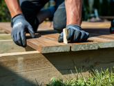 Person working on a wooden structure with tools outdoors