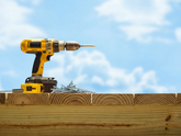Yellow drill on wooden planks with a blue sky background